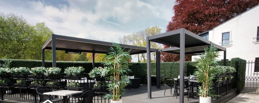 Louvered aluminium pergola over a garden terrace with planting